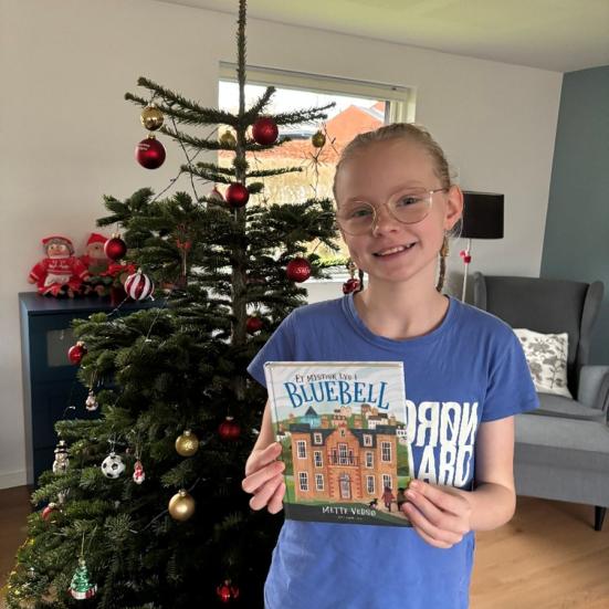 Læseagent Freja med bogen foran et pyntet juletræ