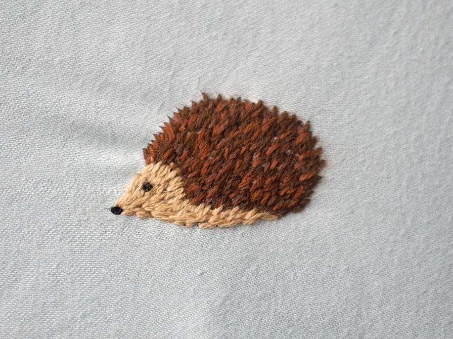 Et hul er lappet med broderi af et lille pindsvin 